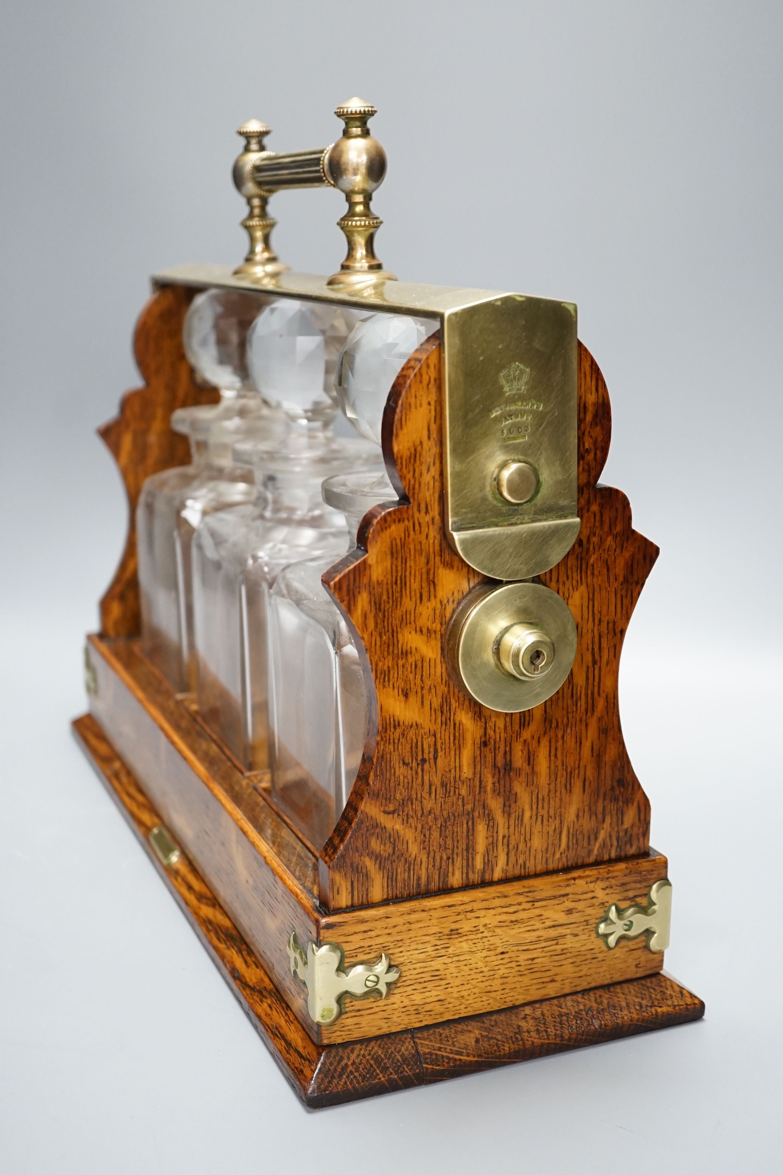 A Victorian Betjemann Patent oak three-bottle Tantalus - 34.5cm high